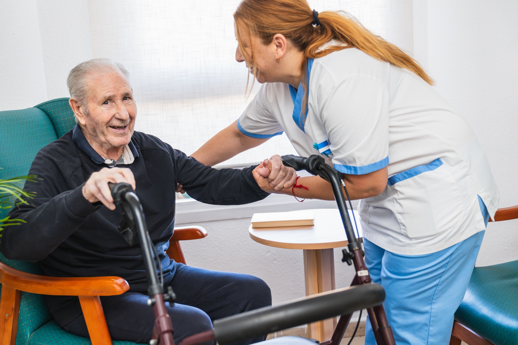 Caring nurse assisting elderly man with walker